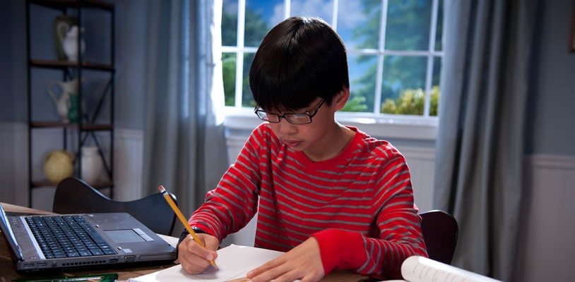 Online private school student writing in a notebook