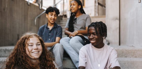 Young teens who take online classes together at Pearson Online Academy are gathered on the steps socializing. 