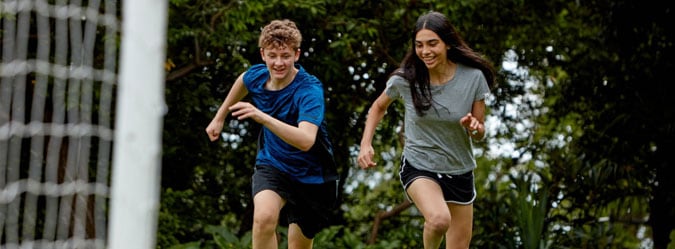 Two high school students playing soccer together