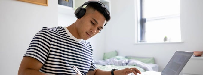 Online private high school student studying on a laptop wearing headphones